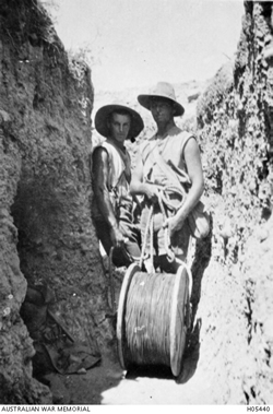 Two men stand in a cutting with a cable drum