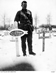 A soldier stands in a snow covered cemetery next to a grave, its cross bearing the words 'No. 2365 L/cpl J.M.Murray 3rd Aust Pioneer [Battalion] AIF' and 'Killed in action 28 7 17'.