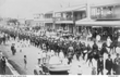 People watch rows of men and soldiers marching down a main street of Taree.