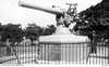 A large gun on a pedestal and ringed by a fence.