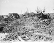 Australian soldiers standing around two fortifications in the middle of a destroyed landscape.