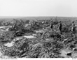 Three soldiers look to the distance as they stand in a landscape destroyed by war and littered with the wreckage.