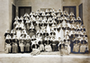 A large group of nurses arranged in tiered rows for a group photograph in front of a building.