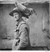 A soldier, facing side on to the camera, has a large rooster standing on his left shoulder.