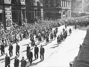 People marching down a city street with crowds lining the side of the road.