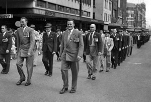 Men wearing medals marching along a city street