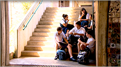 Group of students sitting on steps at school and chatting - link to 'Simon's day'