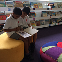 Students looking at a picture book in a school library